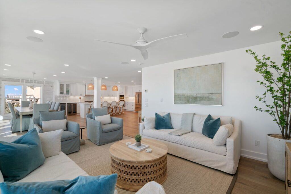 Spacious, modern open-concept living area with neutral tones, comfortable seating, abstract art, and large windows offering scenic outdoor views. No landmarks visible.